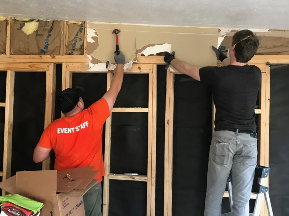 two guys removing damaged drywall