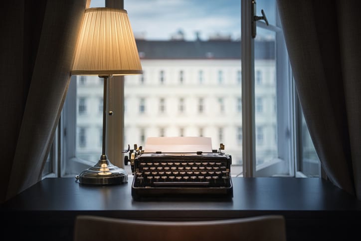 An old typewriter and a lamp on the table.