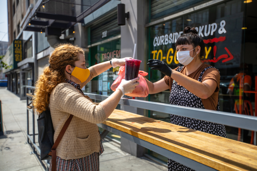 restaurant owner hands an order to a customer outside