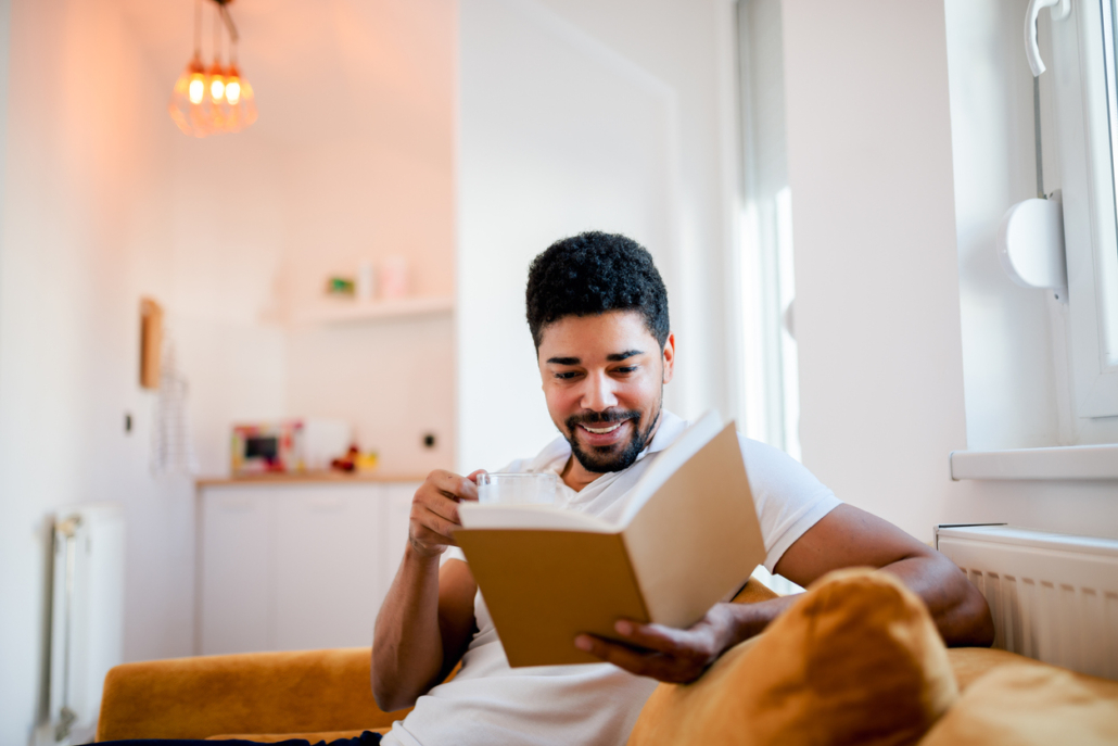 man reading a book while sitting on the sofa