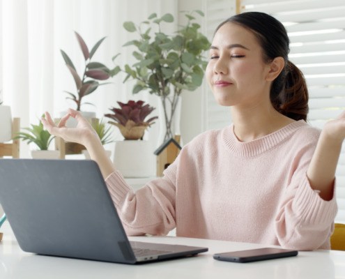 woman meditating in front of laptop