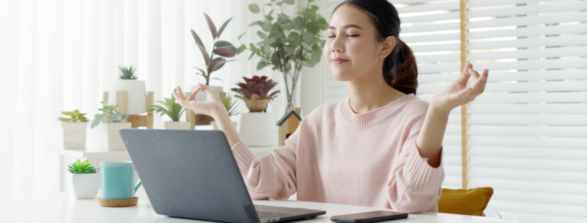 woman meditating in front of laptop