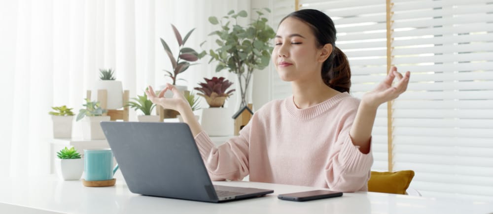 woman meditating in front of laptop