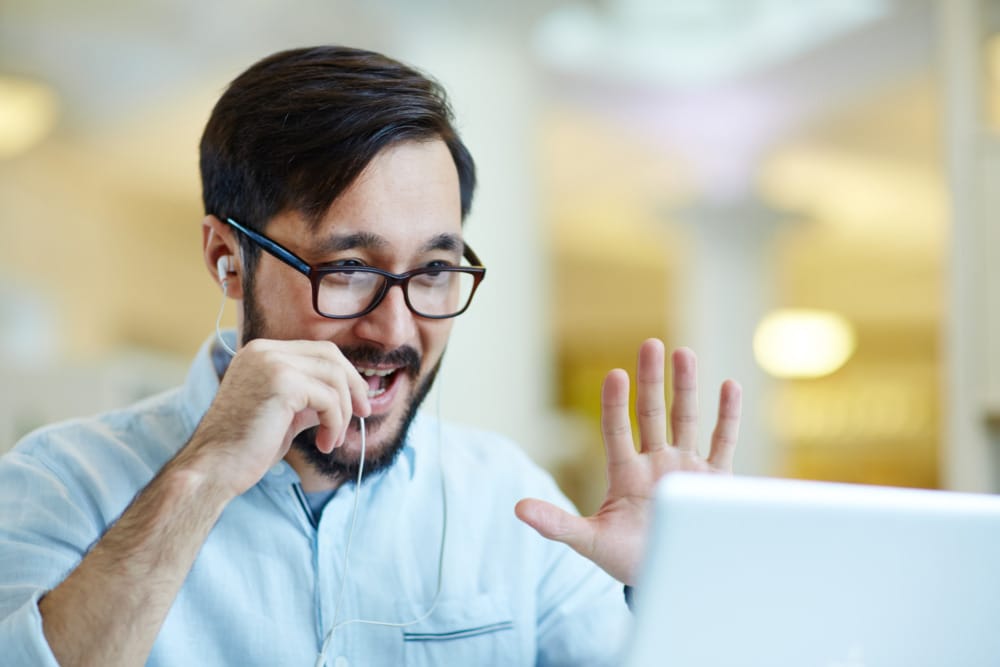 man talking into microphone and waving at computer