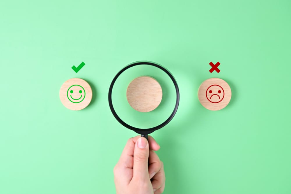 magnifying glass between happy and sad faces