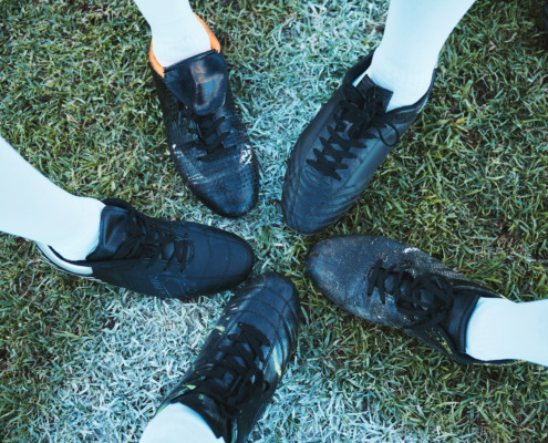 five soccer shoes with toes touching