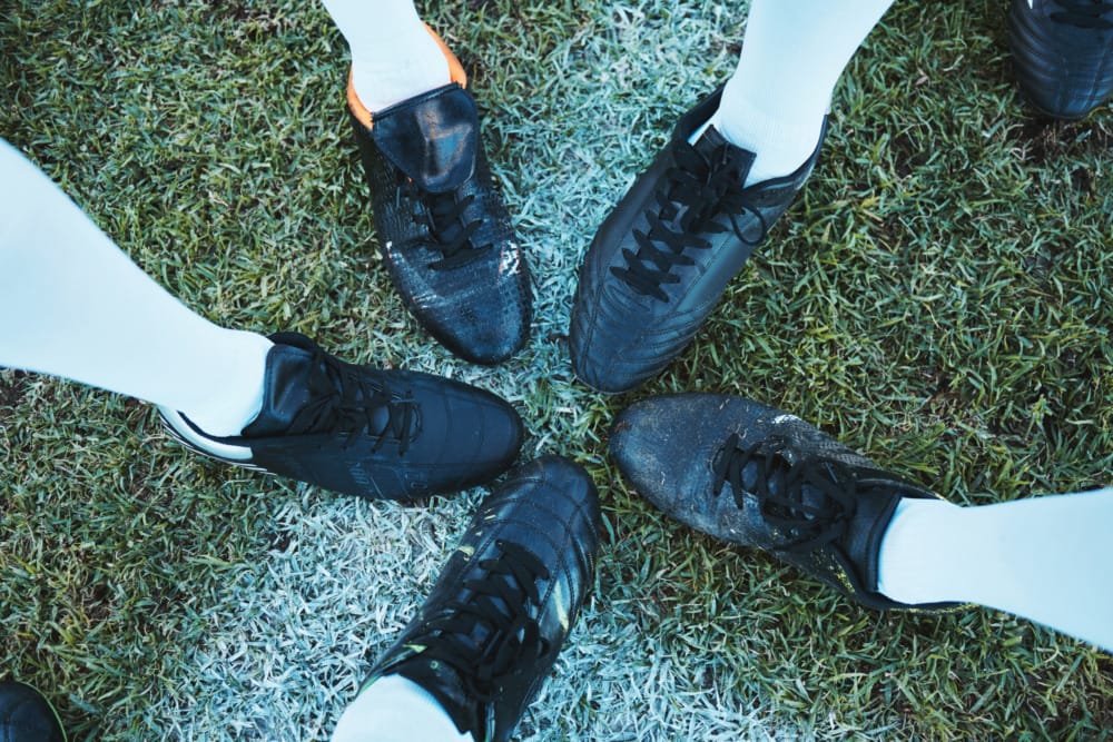 five soccer shoes with toes touching