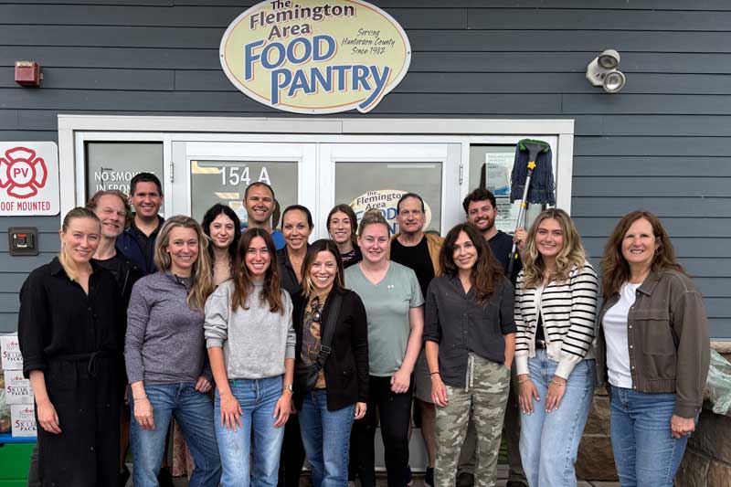 A group of Ideba volunteers standing in front of the doors to the Flemington food pantry.
