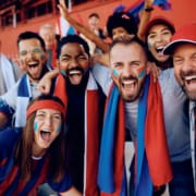 Cheerful fans celebrating the victory of their favorite team at the stadium and looking at camera. Group excited of sports fans shouting from stadium stands and looking at camera.