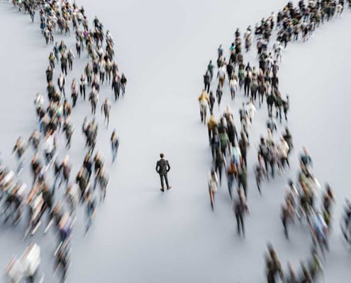 Two lines of people flowing past a business person in the middle.