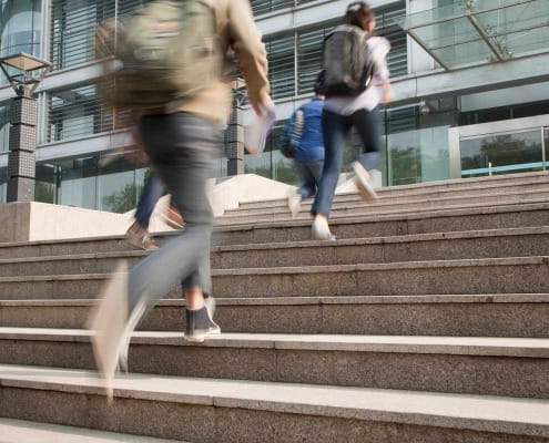 Late students with backpacks running up the stairs to school
