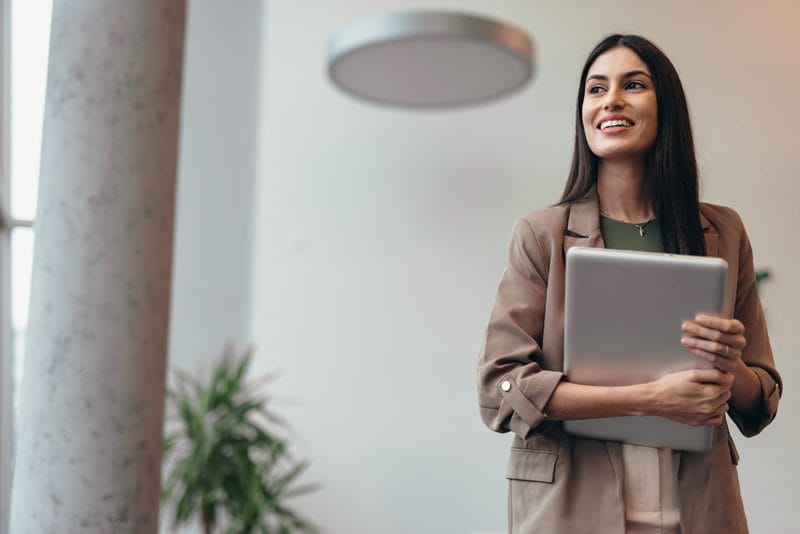 Confident, professional woman holding laptop and looking to her right