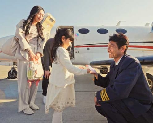 Smiling pilot kneeling and talking to a young girl near an airplane