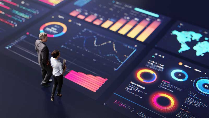 Two executives talking and standing on a giant executive data dashboard