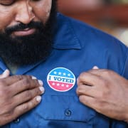 African american man looking at an "I voted sticker" on his chest