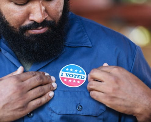 African american man looking at an "I voted sticker" on his chest