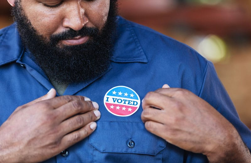 African american man looking at an "I voted sticker" on his chest