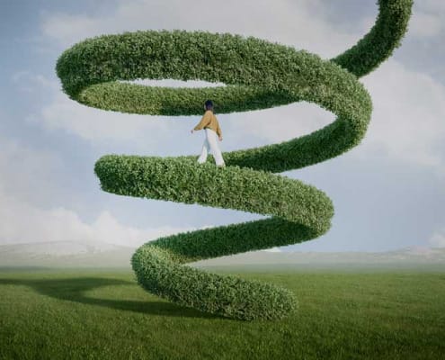 woman walking up a spiral of green hedge