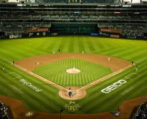 A baseball field at night lit up with players on the bases.