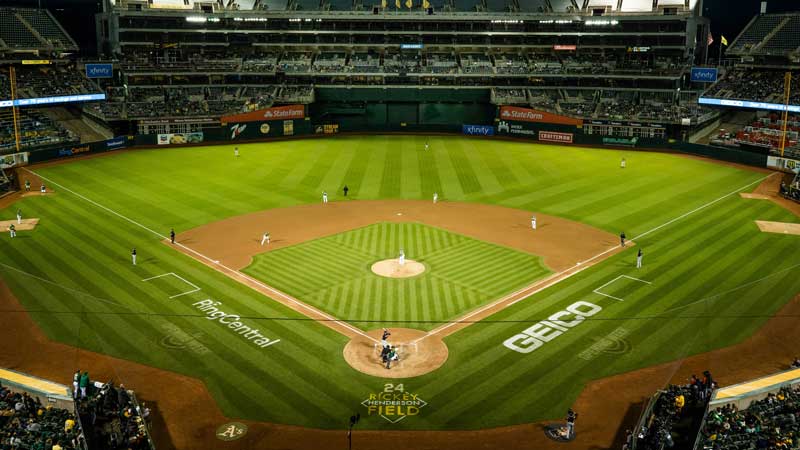 A baseball field at night lit up with players on the bases.