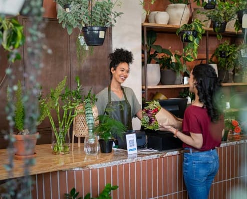 smiling female florist selling a customer flowers