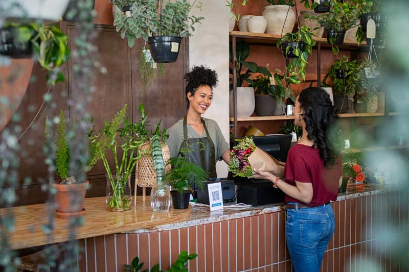 smiling female florist selling a customer flowers