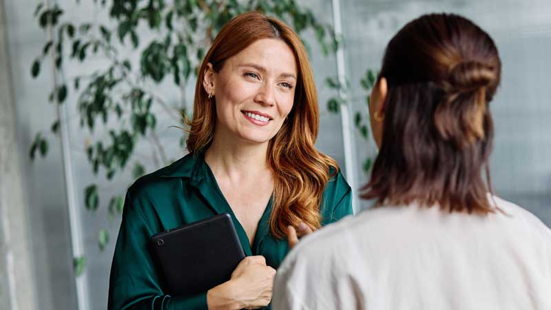 woman smiling while listening to colleague